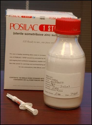 Zdjęcie pokazujące papierowe opakowanie po preparacie Posilac. Przed nim stoi buteleczka z białą cieczą, a na blacie leży strzykawka.